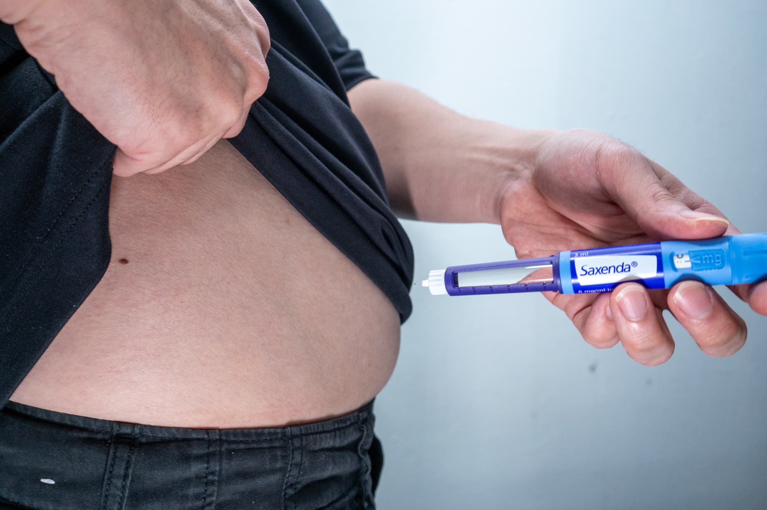 A person subcutaneously administering Saxenda on his abdomen