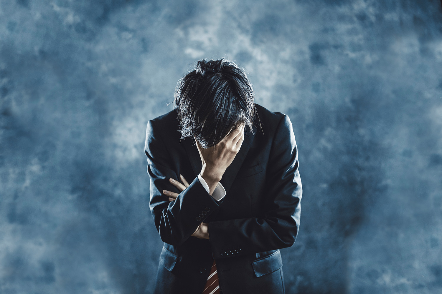 一名沮喪低頭以手掩面的男子