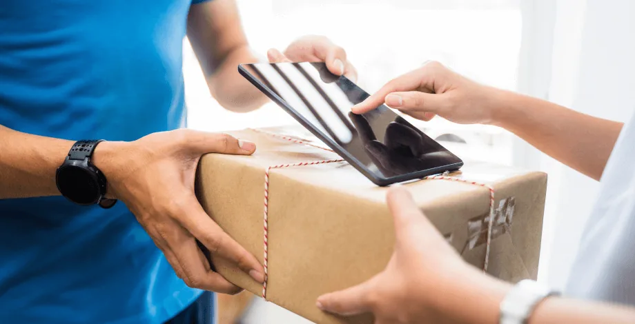 A courier handing a parcel to a man holding a phone