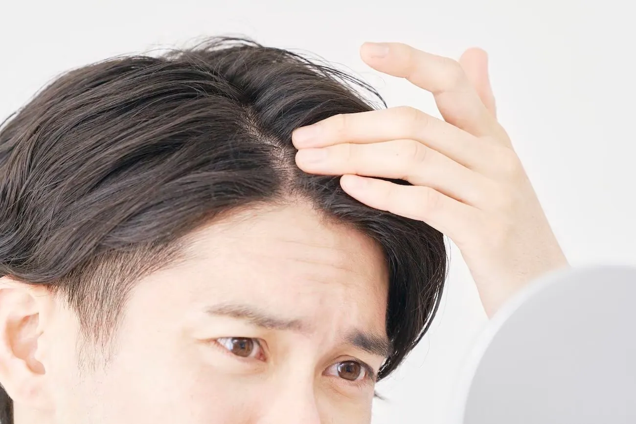 一名男士對著鏡子檢查髮線
